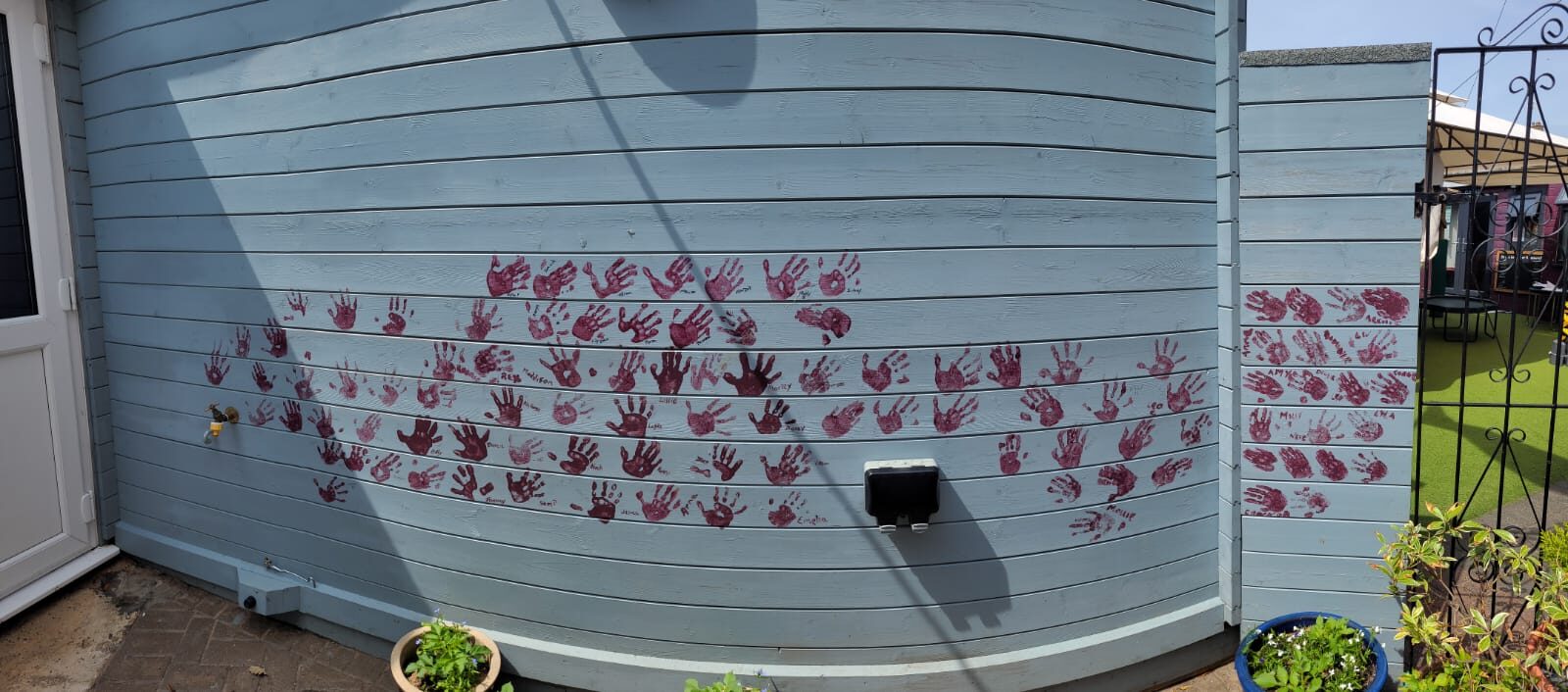 Children's painted handprints on the garden wall