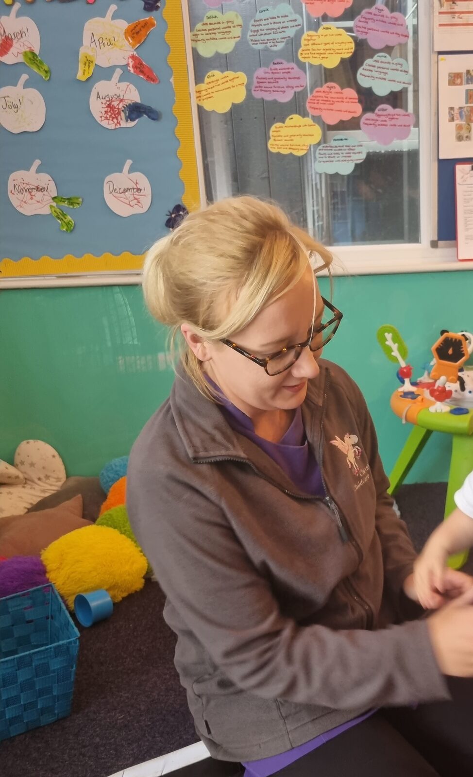 Frances, a member of staff, sitting with a child at Chris's Childcare